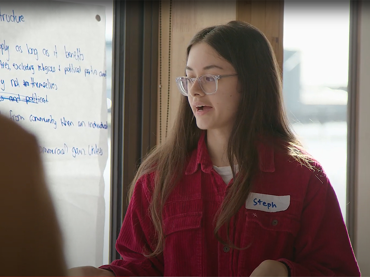 TasNetworks youth panel participant, Name badge says 'Steph' and wearing clear acetate glasses. Looking away from camera and speaking.