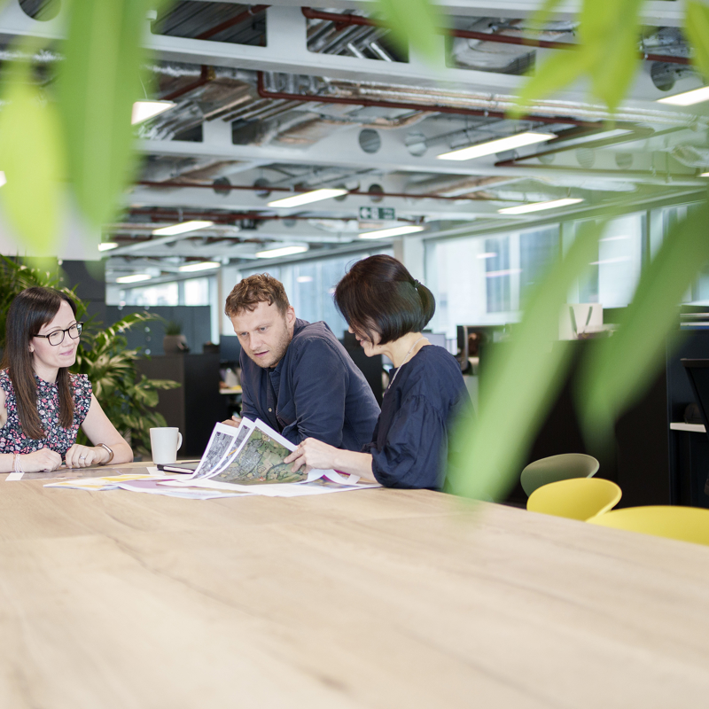 Three colleagues gathered round a table looking at plans