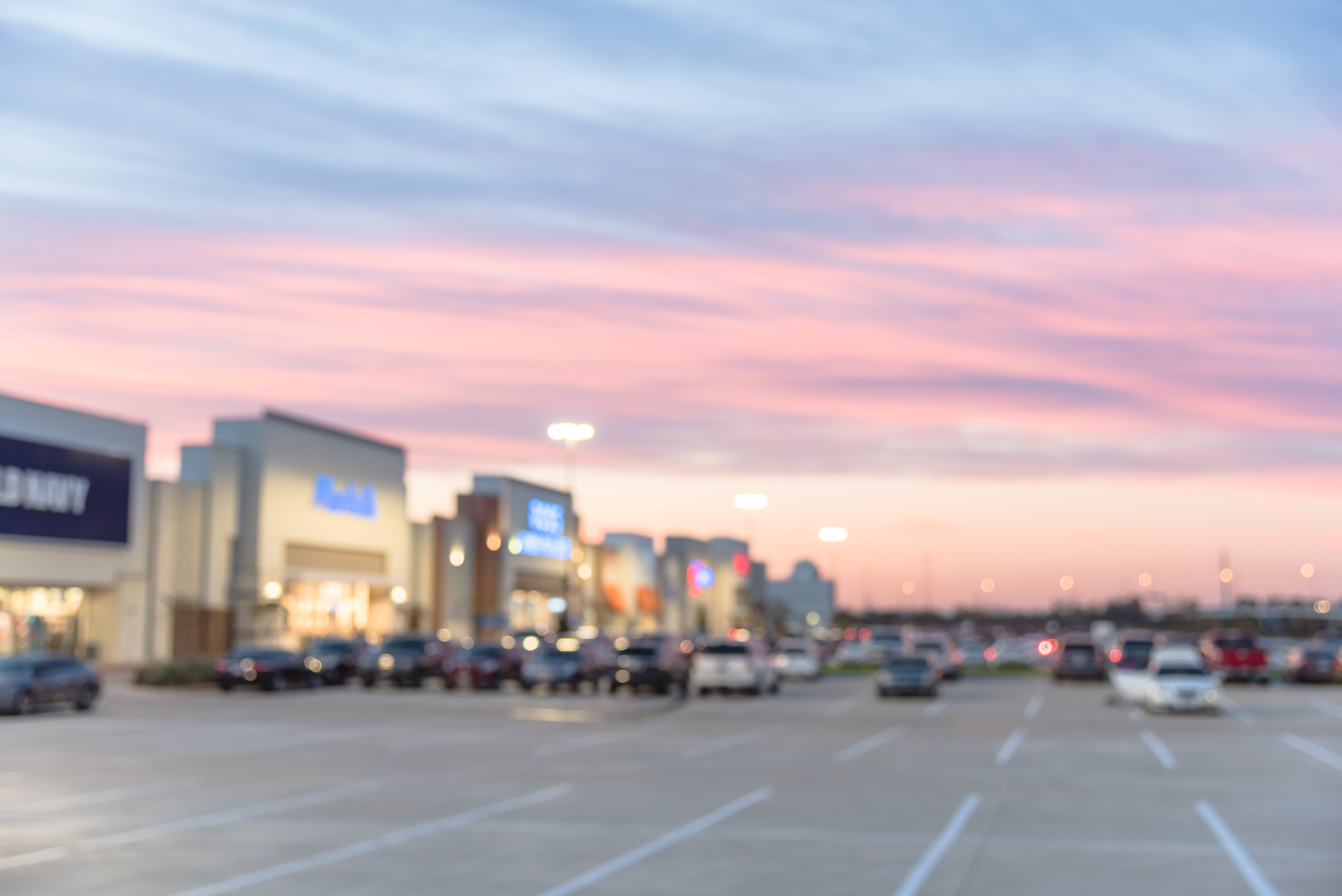 Blurred image of a retail park with a pink sunset