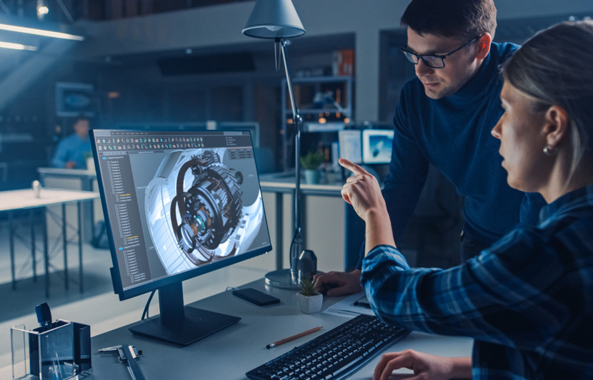 Systems engineer talking to designer over computer with CAD rendered turbine components on screen