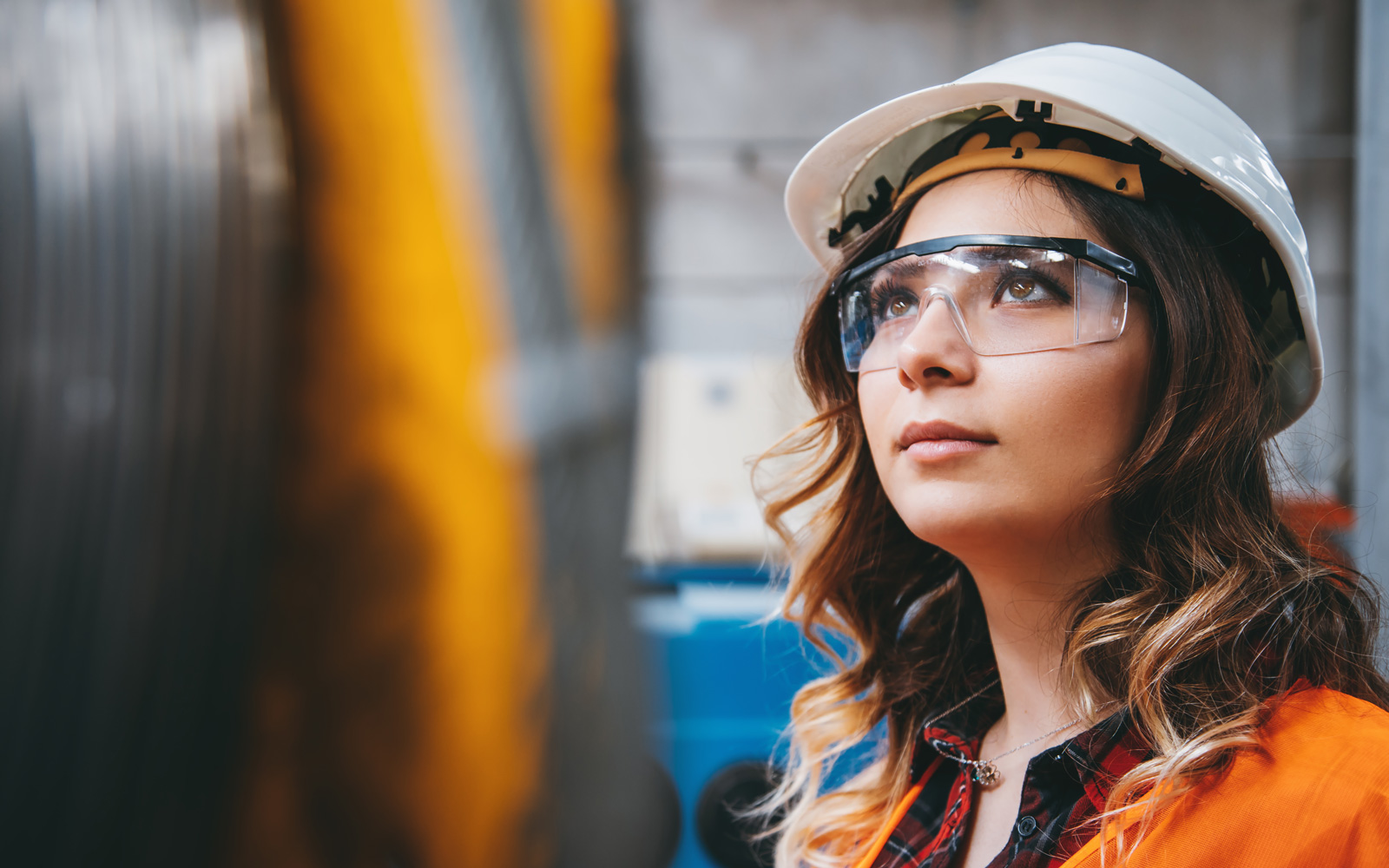 Woman in industry wearing hardhat and safety glasses
