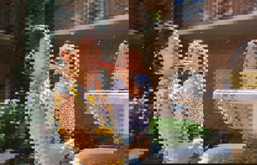 Mother holding young child splashing in fountain