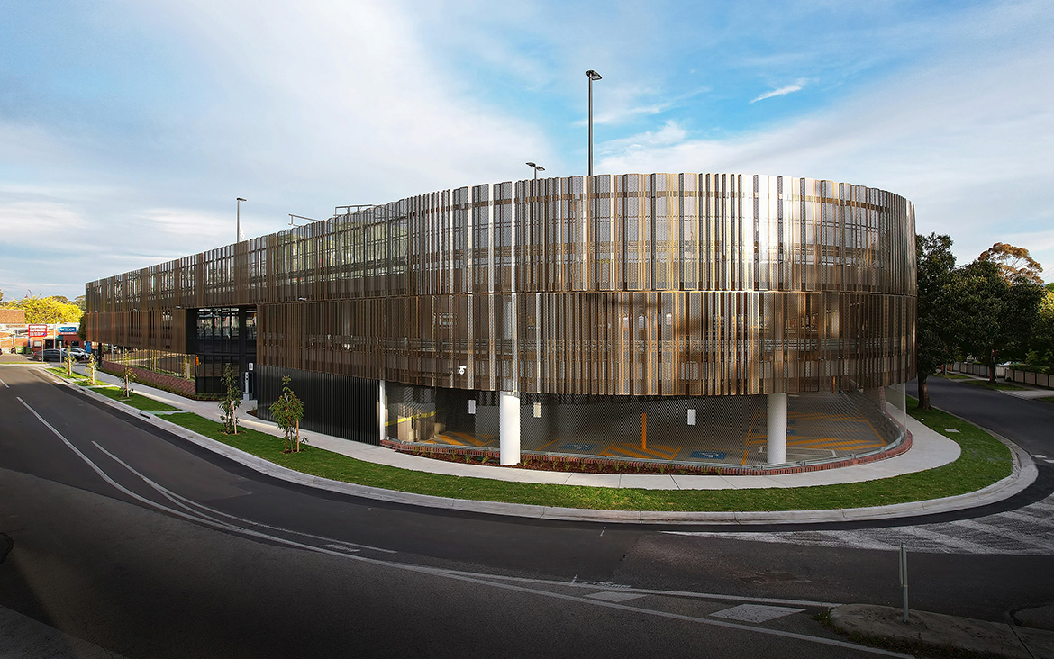 Devon Street Carpark multi-level building featuring architectural metal facade. Photo taken over street in the foreground, pedestrian pathway in front of building and blue skies in the background.