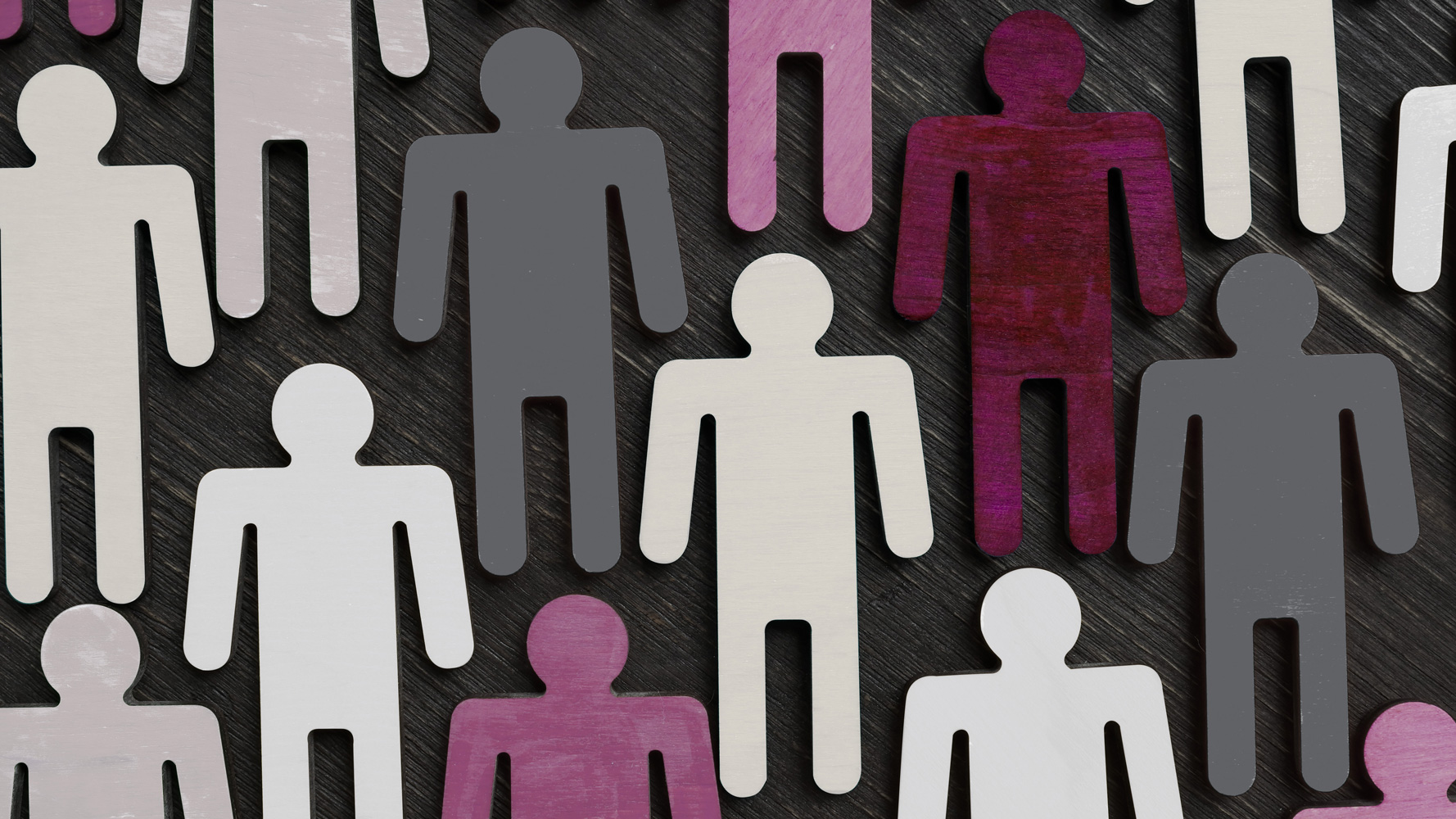 Wooden people cut outs coloured different shades of purple and grey, on a dark background
