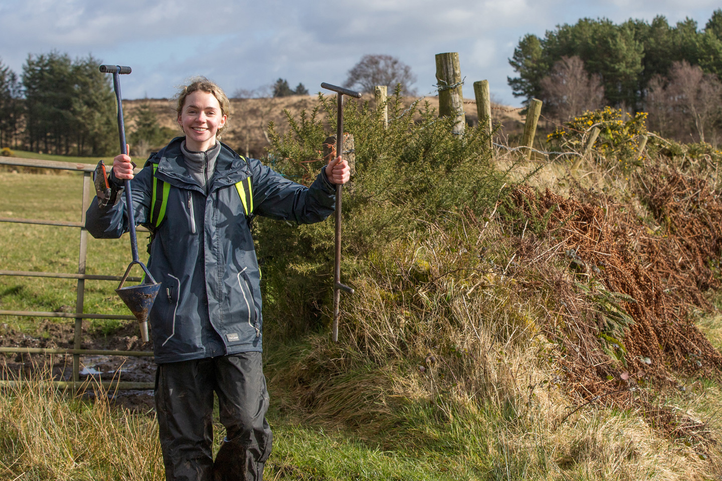 RPS employee stood in agricultural field holding up equipment used for soil sampling