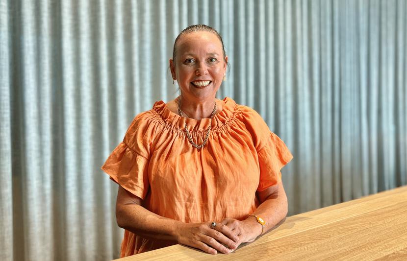 Jeanine Stone, RPS as Technical Director - Planning in Brisbane sits at table and smiles at the camera.