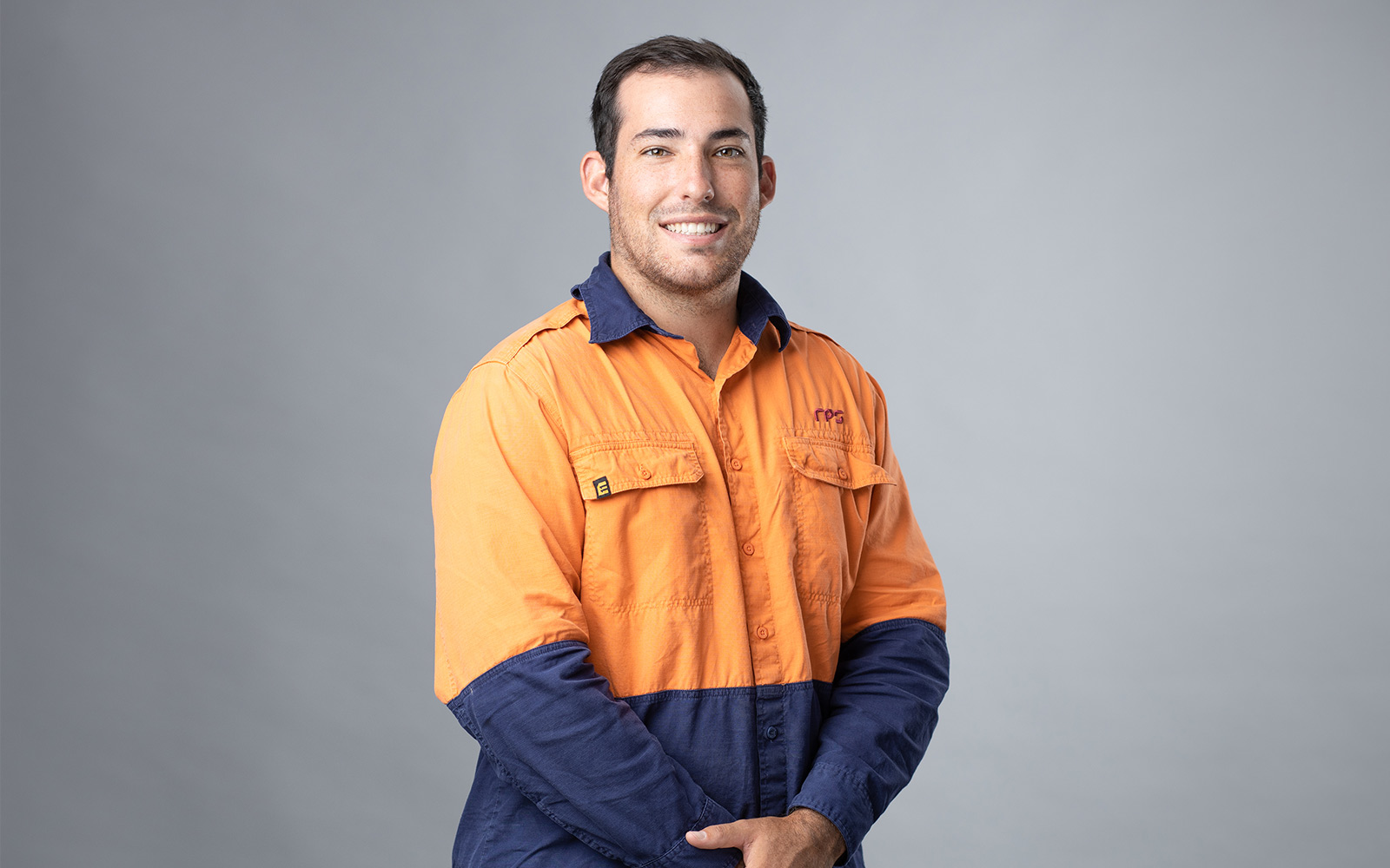 Myles Cassar, Senior Surveyor smiles at the camera wearing high visibility shirt with RPS branding
