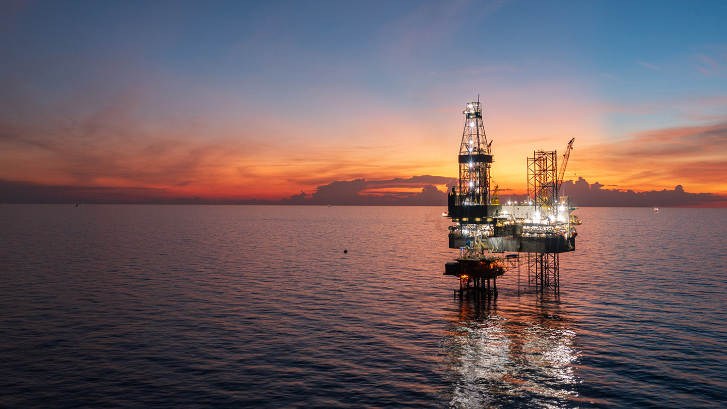 Offshore oil and gas platform at twilight. Lights reflecting in calm water