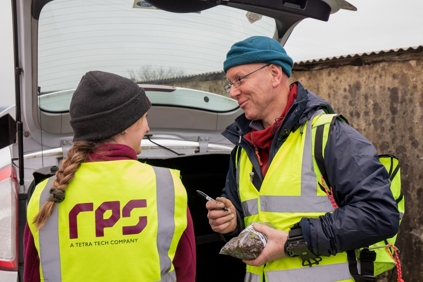 Female and male RPS employees speaking to one another during soil sampling
